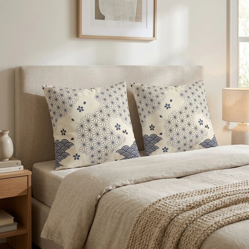 Two pillows with blue Japanese star and wave patterns on a beige bed in a cozy, minimalist bedroom with a wooden nightstand and lamp.