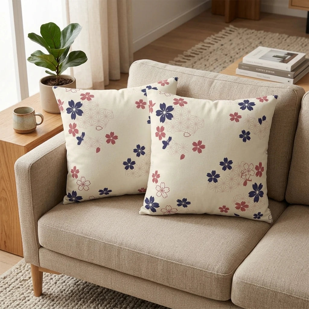 Duo of cream throw pillows with navy and pink cherry blossom floral patterns on a beige sofa in a modern living room lifestyle setting.