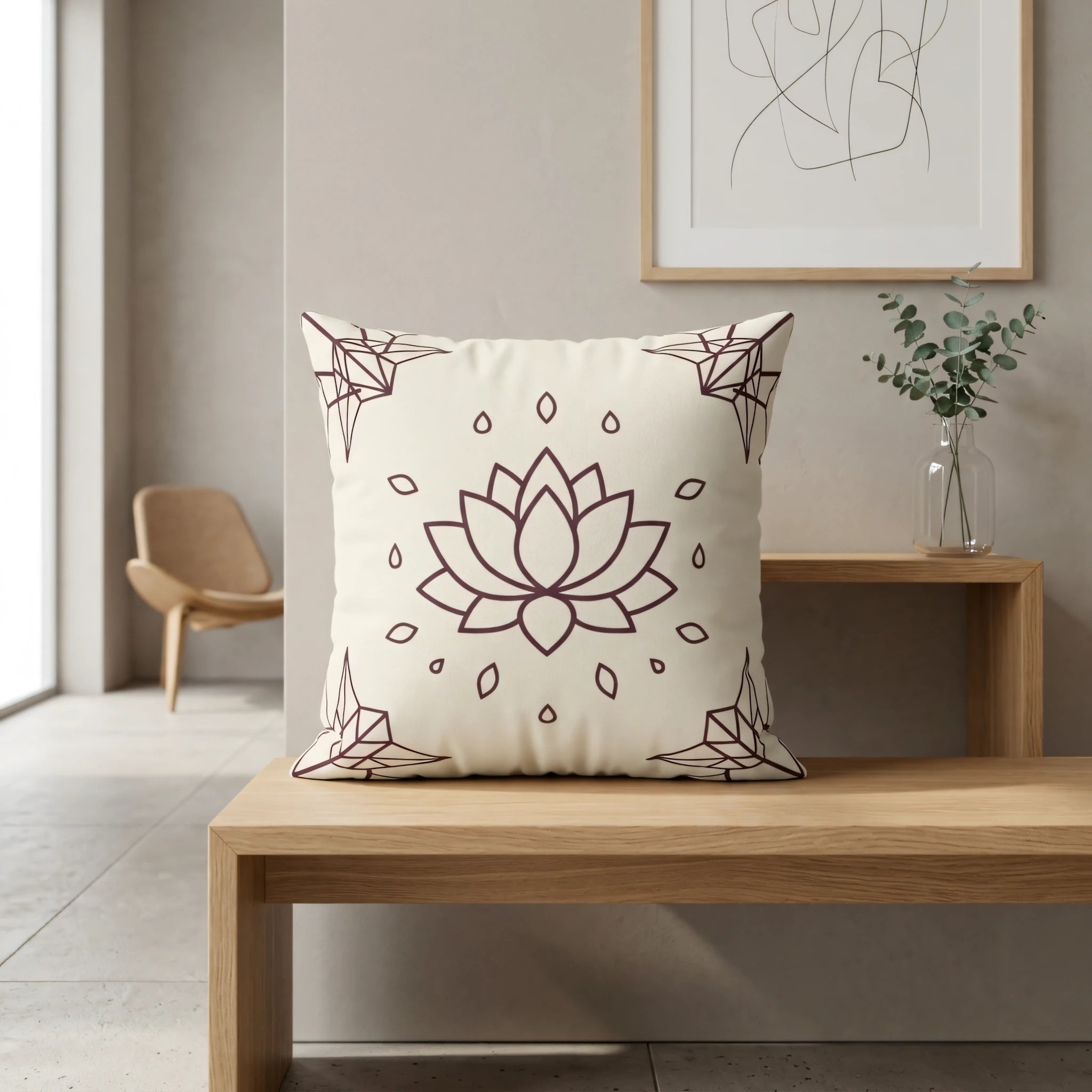Cream throw pillow with a dark burgundy lotus flower pattern on a wooden bench in a minimalist interior featuring neutral tones and modern decor.