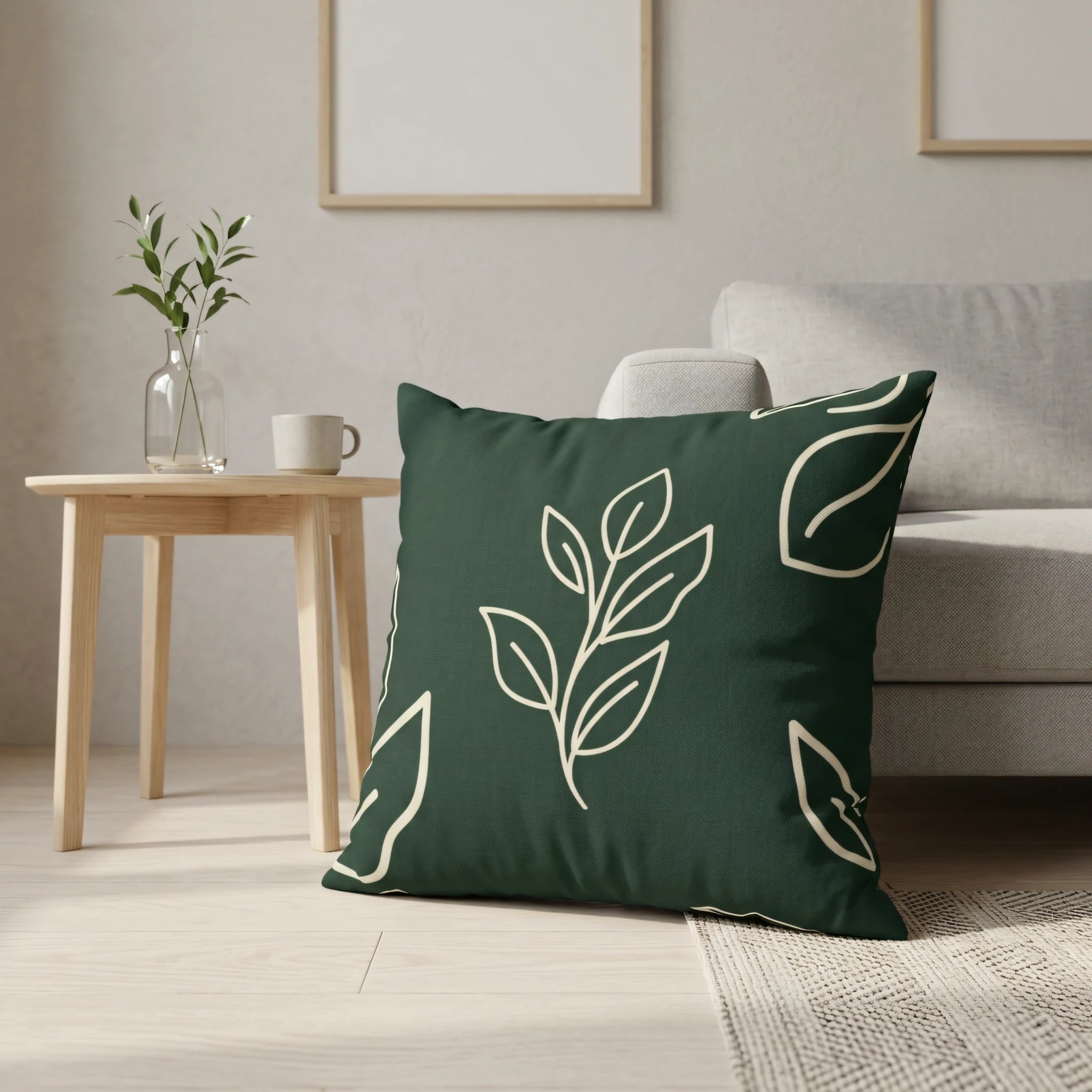 Dark green decorative cushion with a cream leaf pattern in a minimalist interior featuring a light wood side table and light gray sofa.