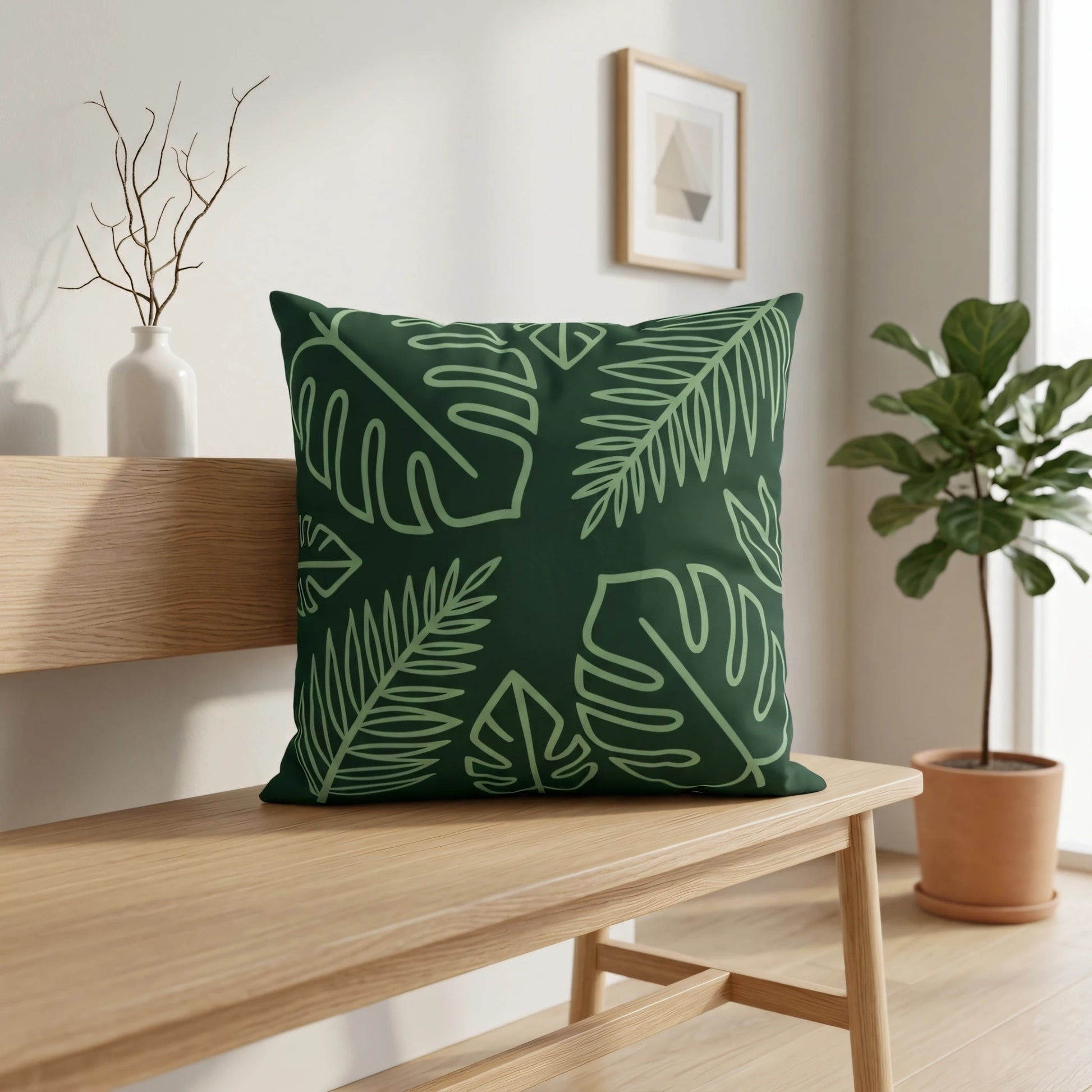 Dark green tropical leaf pattern cushion on a wooden bench in a bright, minimalist interior with a potted plant and framed art.