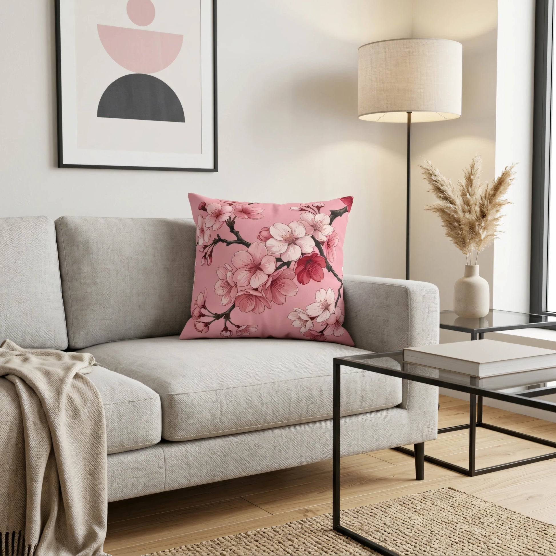Decorative pink cushion with cherry blossom pattern on a light gray sofa in a modern living room with abstract wall art and warm lighting.