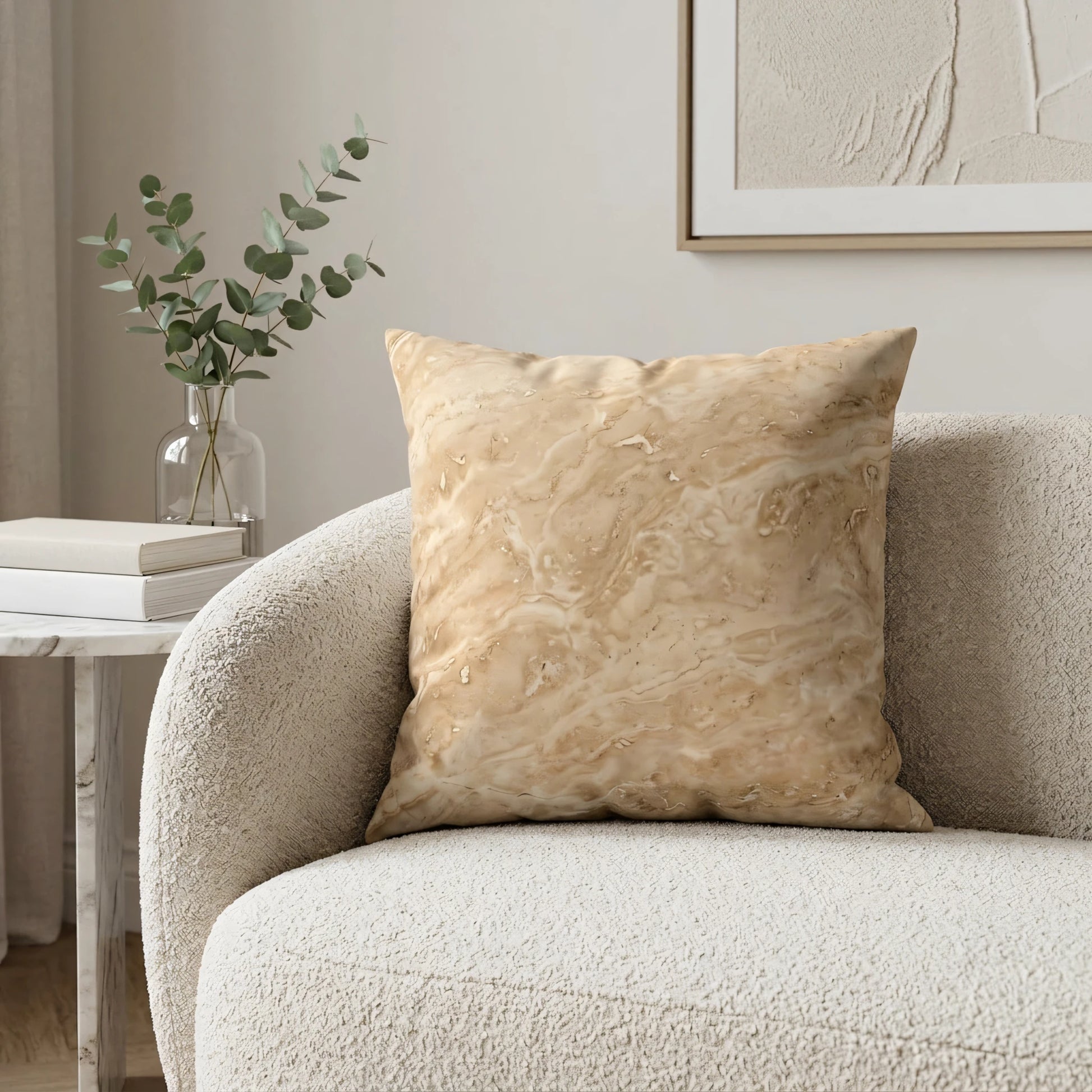 Tan marble pattern decorative cushion on a white boucle sofa with eucalyptus branches and books in a minimalist, bright living room.