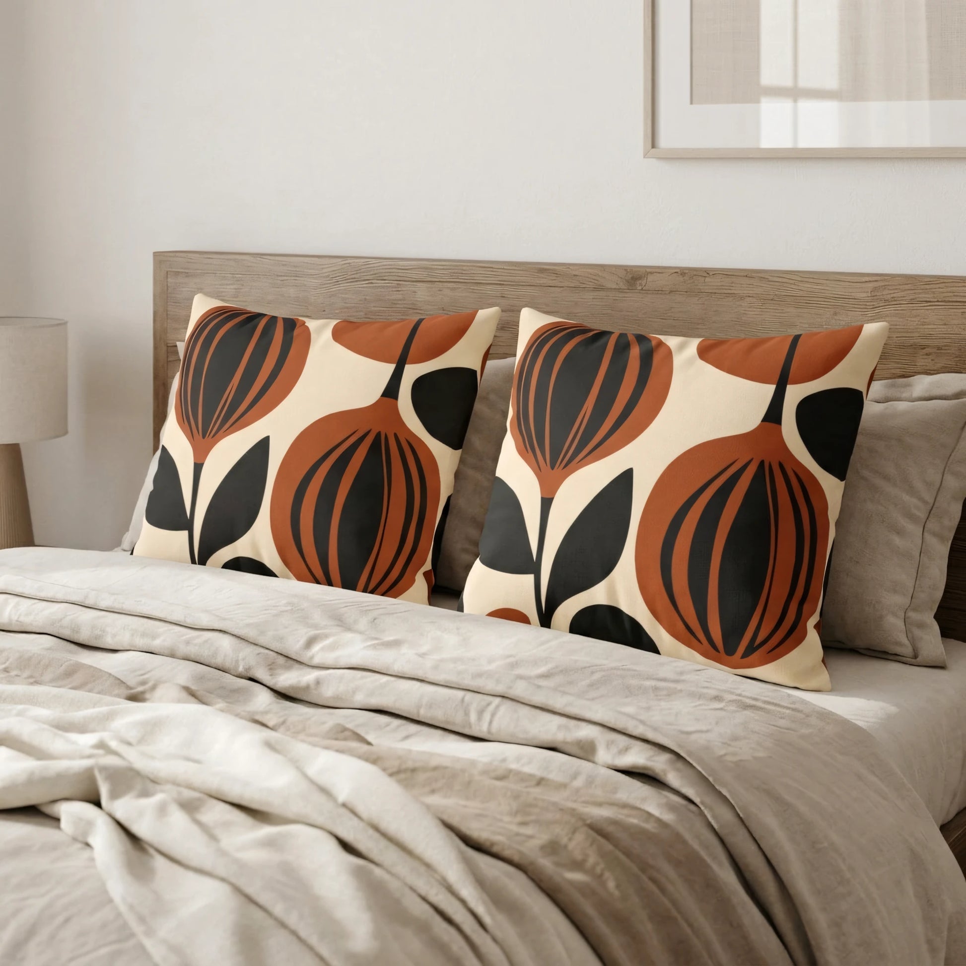 Pair of decorative pillows featuring a bold terracotta and black floral pattern on a neutral bed with beige linens and a wooden headboard.
